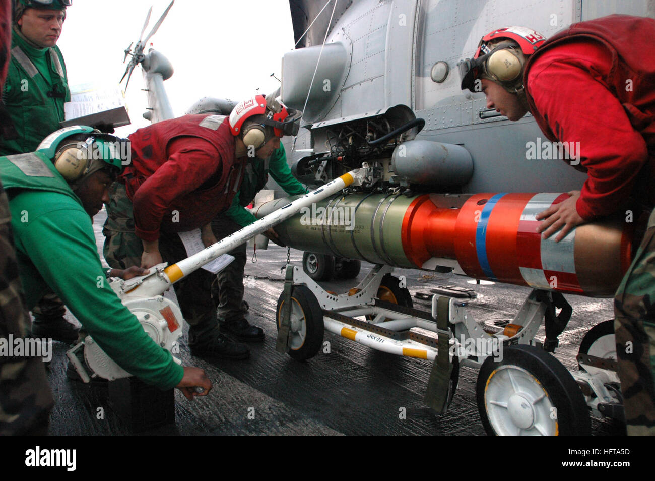 Sailors from HSL-51 load an Mk-46 anti-submarine torpedo onto an SH-60B ...