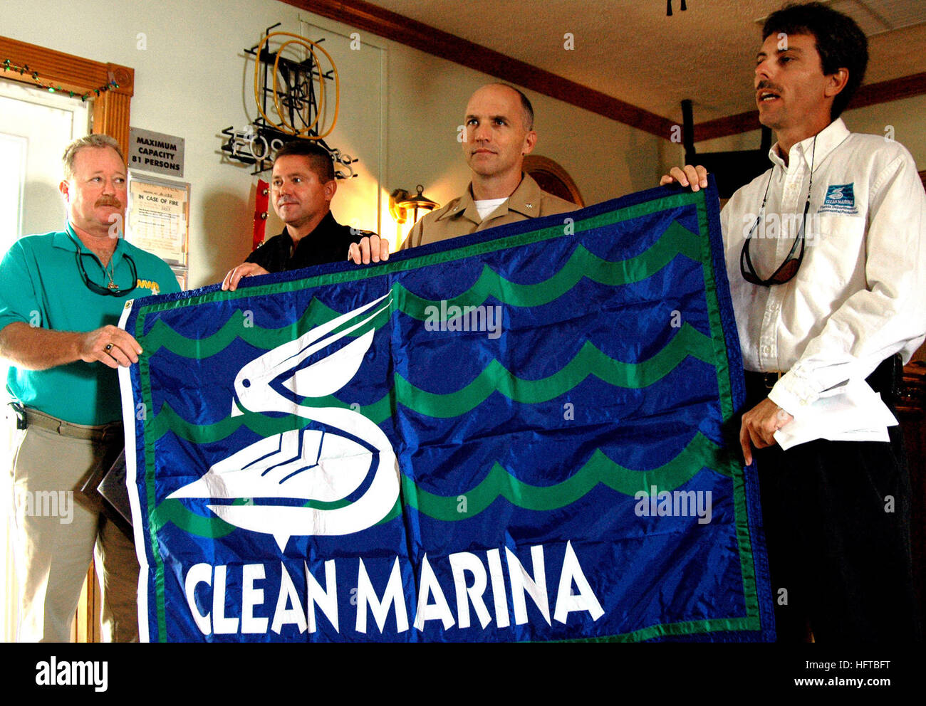061208-N-5240C-010 Key West, Fla. (Dec. 8, 2006) - Clean Marina Coordinator Edward Russell (right) of the Florida Department of Environmental Protection (DEP) presents the 'clean marina' flag to Naval Air Station Key West Executive Officer Cmdr. Hans P. Liske, Command Master Chief Kraig Holubar and Marina Manager Billy Adkins during a ceremony held at the air station. The designation, which recognizes marina facilities for sound environmental stewardship, marked the fifth consecutive year that NAS Key West has met DEP criteria for a clean marina despite sustaining heavy damage as a result of H Stock Photo