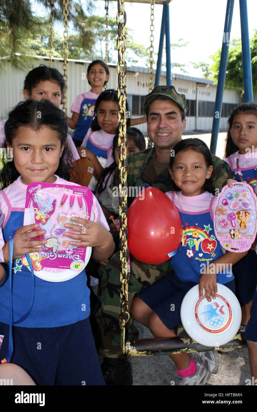 071211-N-3003C-145 COMALAPA, El Salvador (Dec. 11, 2007)  Yeoman 1st Class Joel De Los Santos, assigned to Forward Operating Location (FOL) Comalapa, sits on a swing with children orphanage while they play with gifts they received during a community relation project at the ÒHogar Del NinoÓ Orphanage in San Salvador, El Salvador. The toys were part of a Project Handclasp donation sent to FOL Comalapa for community relations projects. U.S. Navy photo by Mass Communication Specialist 3rd Class Brett Custer (Released) US Navy 071211-N-3003C-145 Yeoman 1st Class Joel De Los Santos, from Forward Ope Stock Photo