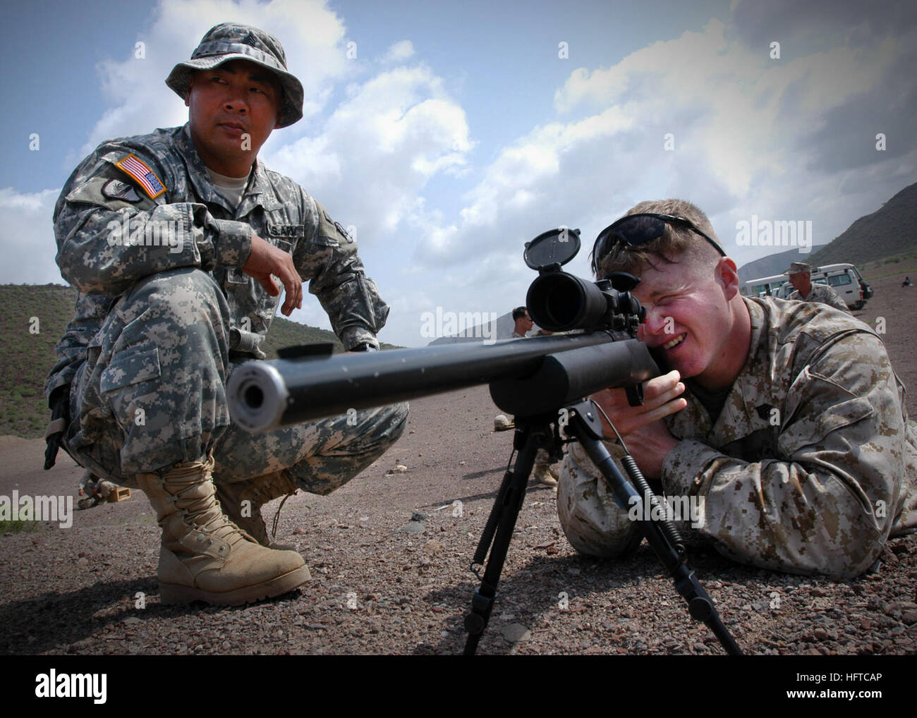 061223-N-1328C-509 Arta, Djibouti (Dec. 23, 2006) - Army Sgt. Mijung Kim, left, from Harmon, Guam, observes Marine Corps Sgt. John Rheuby, from Hueytown, Ala., as Rheuby fires an M-24 rifle during a familiarization shoot. Kim is currently deployed with Team Charlie of the 1st Battalion of the 294th Infantry, and Rheuby is deployed to the 5th Provisional Security Company (5th PSC). Team Charlie provides military-to-military training and force protection throughout the Horn of Africa region. The 5th PSC is responsible for the security at Camp Lemonier, Djibouti, the home of Combined Joint Task F Stock Photo