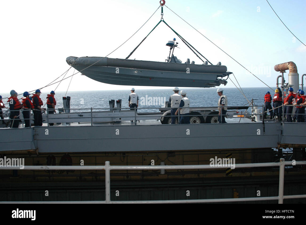 070110-N-1952L-002 U.S. Naval Forces Central Command Area of Responsibility (Jan. 10, 2007) - Deck Department aboard the Whidbey Island-class dock landing ship USS Ashland (LSD 48) use a crane to lower one of its Rigid Hull Inflatable Boats (RHIB) into the water. A RHIB is the primary means of transportation for its Visit, Board, Search and Seizure (VBSS) teams. Ashland is on a regularly scheduled deployment in support of Maritime Security Operations (MSO). MSO help set the conditions for security and stability in the maritime environment, as well as complement the counter-terrorism and securi Stock Photo