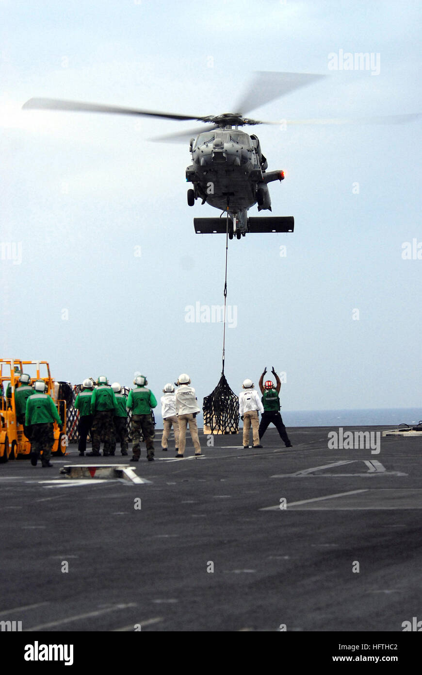 070314-N-3659B-070 PACIFIC OCEAN (March 14, 2007) - A landing signalman enlisted (LSE) sends hand signals to the pilot of an MH-60S Seahawk, assigned to the "Island Knights" of Helicopter Sea Combat Squadron (HSC) 25, while it delivers supplies to Nimitz-class aircraft carrier USS Ronald Reagan (CVN 76). Reagan participated in an early morning replenishment with the Military Sealift Command (MSC) combat stores ship USNS Niagara Falls (T-AFS 3) to bring food and supplies to Reagan. Ronald Reagan Carrier Strike Group and embarked Carrier Air Wing (CVW) 14 are underway in support of operations in Stock Photo