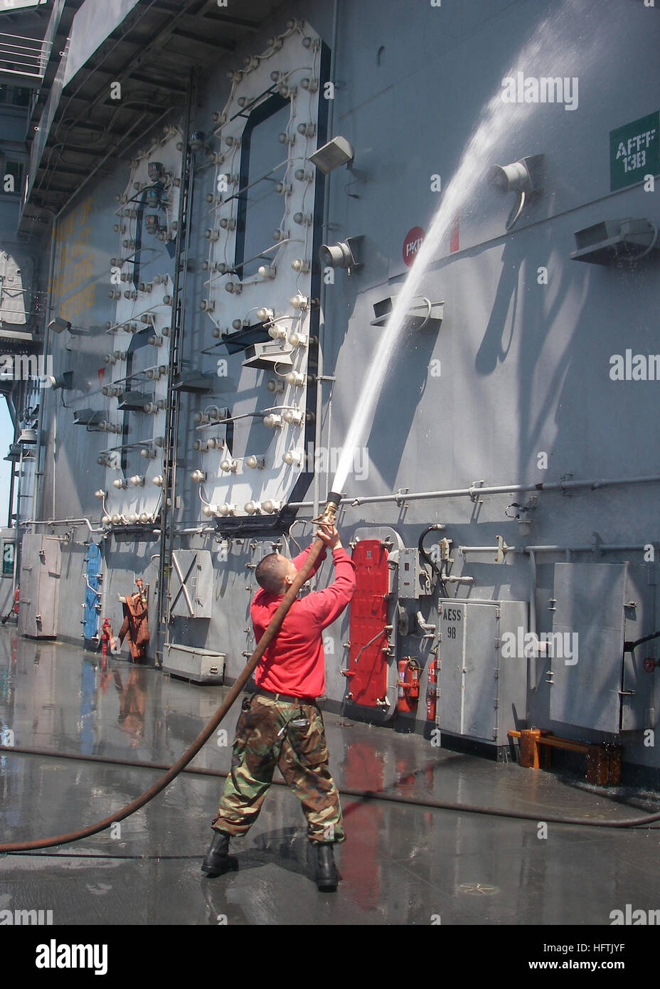 A Sailor performs a fresh water rinse after a countermeasure washdown