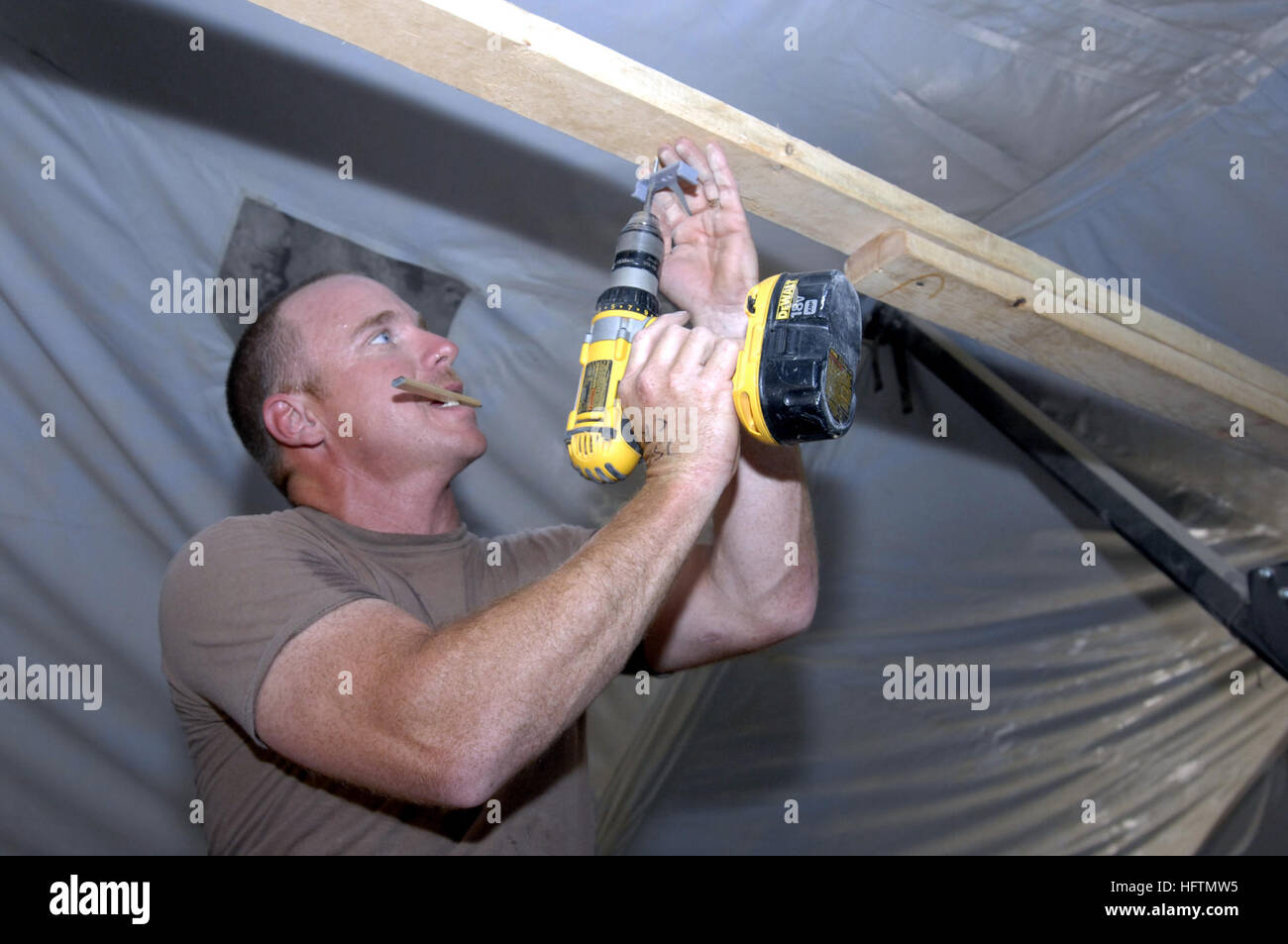 070426-N-4928M-055 COMBAT OUTPOST RAWA, Iraq (April 26, 2007) - Builder 2nd Class Gregory Winters, a Navy Reservist from Tyler, Texas, prepares to hang fixed lighting in a 1st Light Armored Reconnaissance Battalion housing tent at Combat Outpost Rawa. Tyler is assigned to Naval Mobile Construction Battalion (NMCB) 28. The regiment, commanded by Capt. Katherine Gregory, provides critical construction for the 2nd Marine Expeditionary Force (II MEF) in support of the global war on terrorism. U.S. Navy photo by Senior Chief Mass Communication Specialist Jon E. McMillan (RELEASED) US Navy 070426-N- Stock Photo