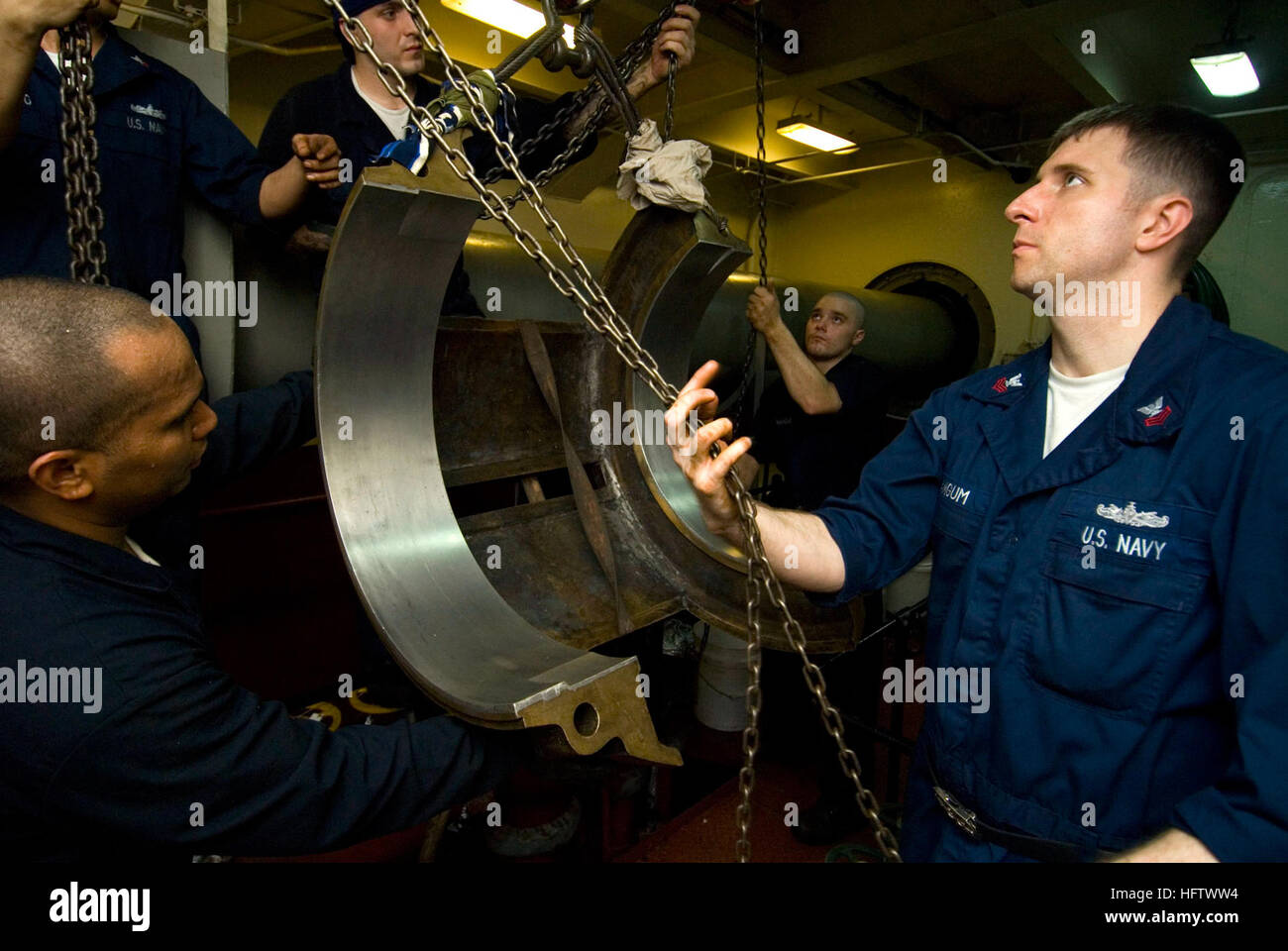 070802-N-9864S-012 PACIFIC OCEAN (Aug. 2, 2007) - Machinist's Mate 1st Class Eddie Mangum raises the upper shell of one of the USS Kitty Hawk's (CV 63) shaft bearing housings with a chain fall while the shell is being removed.  Once the shell is removed and placed upside down, the Sailors will be able to see any grooves cut into it by the shaft. They will then smooth out the shaft and shell to get a perfect fit. Kitty Hawk is entering its 3rd month of a summer deployment from Fleet Activities Yokosuka, Japan. U.S. Navy photo by Mass Communication Specialist Joseph R Schmitt (RELEASED) US Navy  Stock Photo