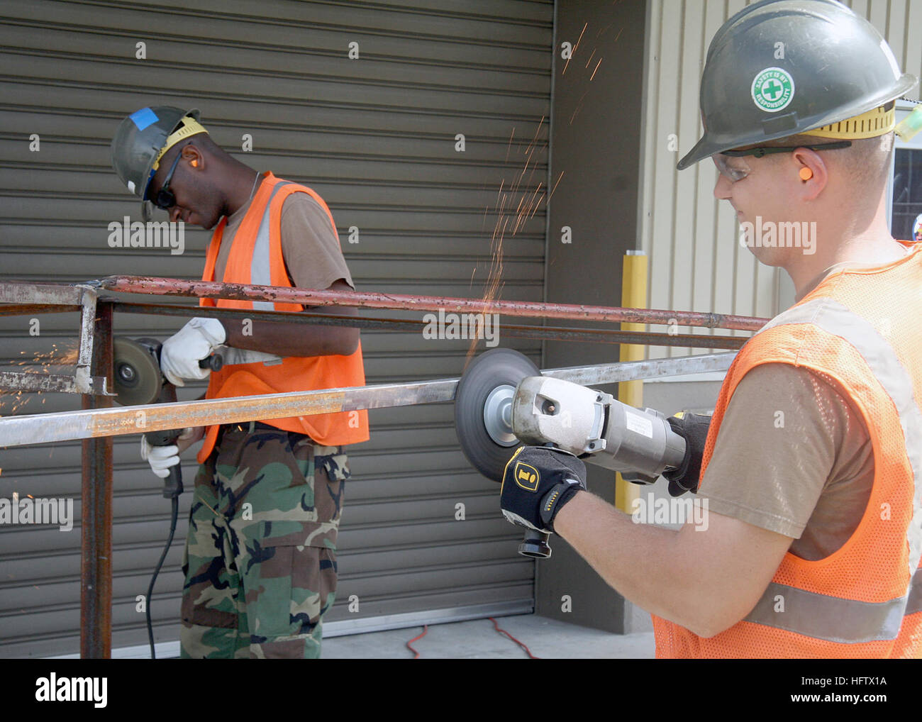 070807-N-5277R-002  ATSUGI, Japan (Aug. 7, 2007) - Utilitiesman 2nd Class Brent Zimmerman, right, and Utilitiesman Constructionman Apprentice Charles Olise, both of Naval Air Facility AtsugiÕs Public Works Department, grind rust off a steel frame. Once complete, the piece will be used to assemble a decontamination trailer for NAFÕs Disaster Preparedness Office. U.S. Navy photo by Mass Communication Specialist Seaman Barry Riley (RELEASED) US Navy 070807-N-5277R-002 Utilitiesman 2nd Class Brent Zimmerman, right, and Utilitiesman Constructionman Apprentice Charles Olise, both of Naval Air Facili Stock Photo