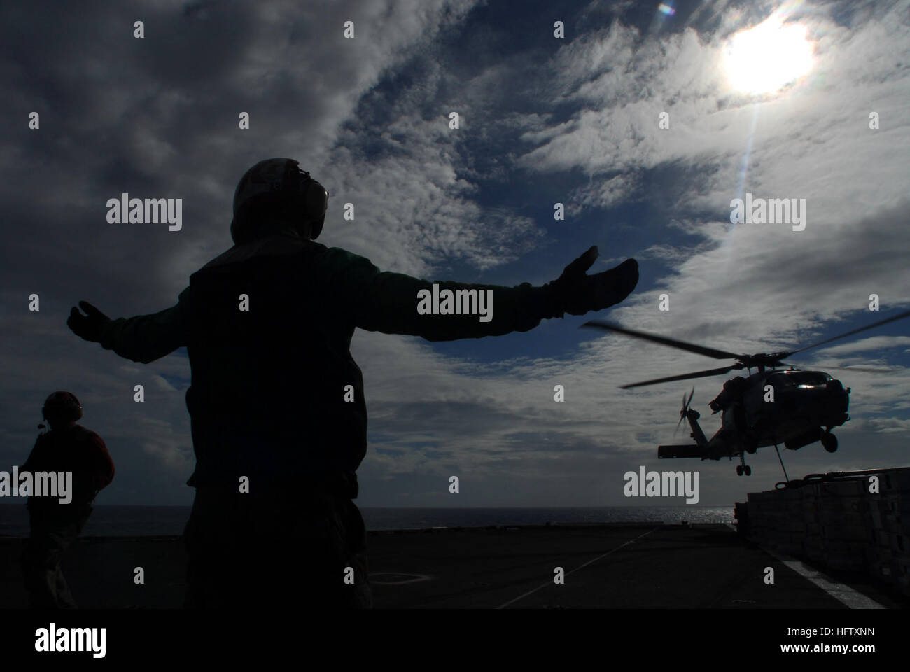 070818-N-2659P-222 PACIFIC OCEAN (Aug. 18, 2007) - Aviation Ordnanceman 3rd Class Roger Sparks signals for a HH-60H Seahawk, attached to the 'Eightballers' of Helicopter Anti-Submarine Squadron (HS) 8, to lift up from the loading area of the flight deck of Nimitz-class aircraft carrier USS John C. Stennis (CVN 74). Stennis is transferring ammunition to the Military Sealift Command ammunition ship USNS Flint (T-AE 32) during a weapons off-load. Stennis, and Carrier Air Wing 9, as part of the John C. Stennis Carrier Strike Group, are on a regularly scheduled deployment to promote peace, regional Stock Photo