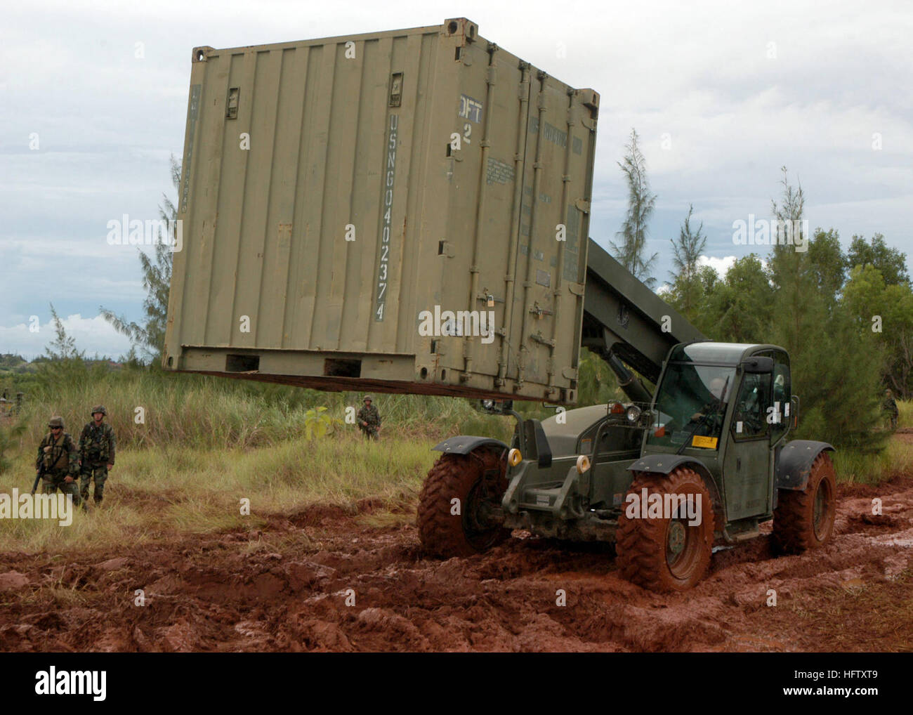 070820-F-8678B-050 GUAM (Aug. 20, 2007) Ð Construction Mechanic 1st Class Kenneth E. Terlaan drives a extendable boom forklift through the mud to position a CONEX box containing the field armory during setup for a field exercise. Naval Mobile Construction Battalion 4 is deployed to Guam in support of construction requirements for Pacific Command. U.S. Air Force photo by Air Force Master Sgt. Rickie D. Bickle (RELEASED) US Navy 070820-F-8678B-050 Construction Mechanic 1st Class Kenneth E. Terlaan drives a extendable boom forklift through the mud to position a CONEX box containing the field armo Stock Photo