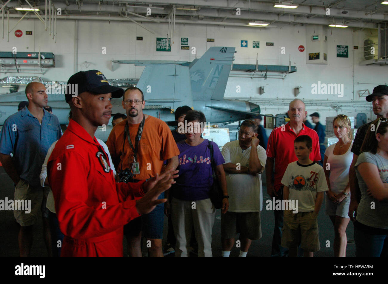 080704-N-2757S-015 PEARL HARBOR, Hawaii (July 4, 2008) Lt. Jameel McDaniel, assigned to Helicopter Anti-Submarine Squadron Light (HSL) 51, talks to a group of visitors during a tour in the hangar bay of the aircraft carrier USS Kitty Hawk (CV 63). The ship is at Pearl Harbor for Rim of the Pacific (RIMPAC) 2008 with units from Australia, Chile, Japan, the Netherlands, Peru, South Korea, Singapore, and the United Kingdom.  Taking part are 35 ships, six submarines, more than 150 aircraft, and 20,000 Sailors, airmen, Marines, soldiers and Coast Guardsmen. U.S. Navy photo by Mass Communication Sea Stock Photo