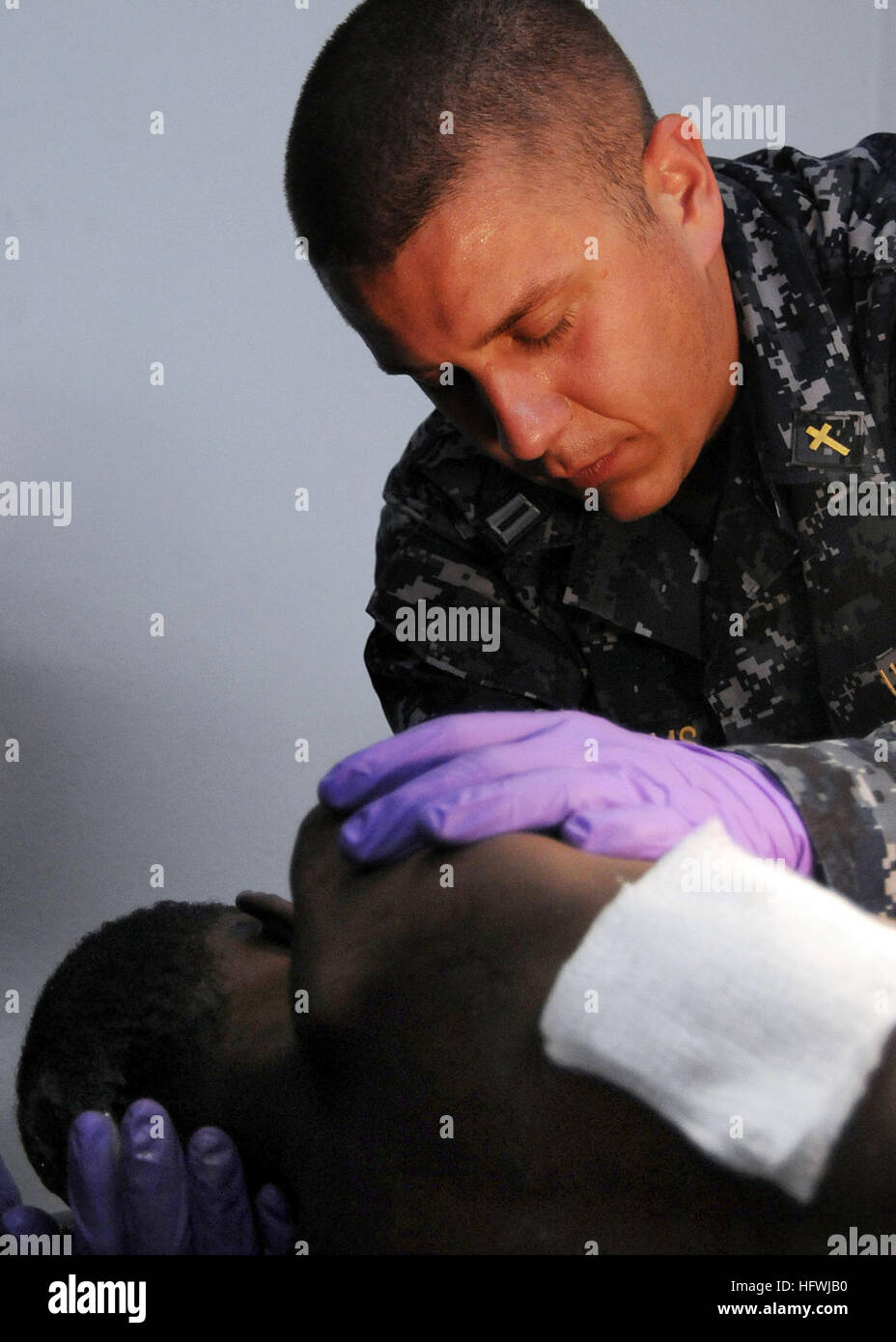 100120-N-6247V-034 KILLICK, Haiti (Jan. 20, 2010) Lt. Marlin Williams, a Navy chaplain embarked aboard the aircraft carrier USS Carl Vinson (CVN 70), prays for a Haitian boy as he receives treatment at the Killick Haitian Coast Guard Clinic. The boy was trapped under the bodies of dead family members in a collapsed building for seven days before he was rescued from the rubble. Carl Vinson and Carrier Air Wing (CVW) 17 are conducting humanitarian and disaster relief operations as part of Operation Unified Response after a 7.0 magnitude earthquake caused severe damage near Port-au-Prince on Jan. Stock Photo