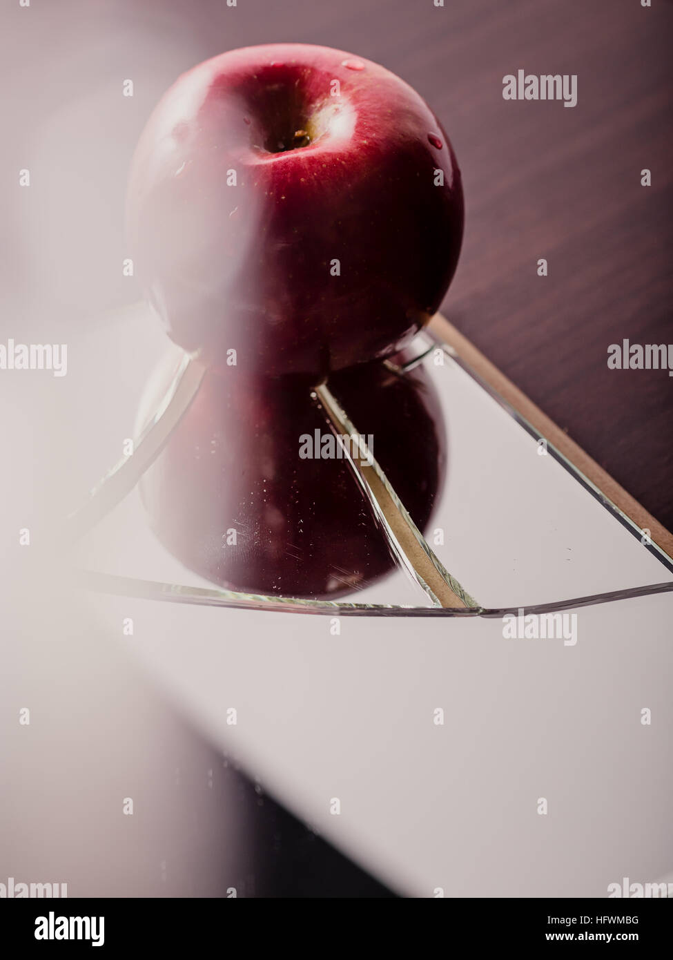 Red apple on cracked broken mirror reflecting Stock Photo