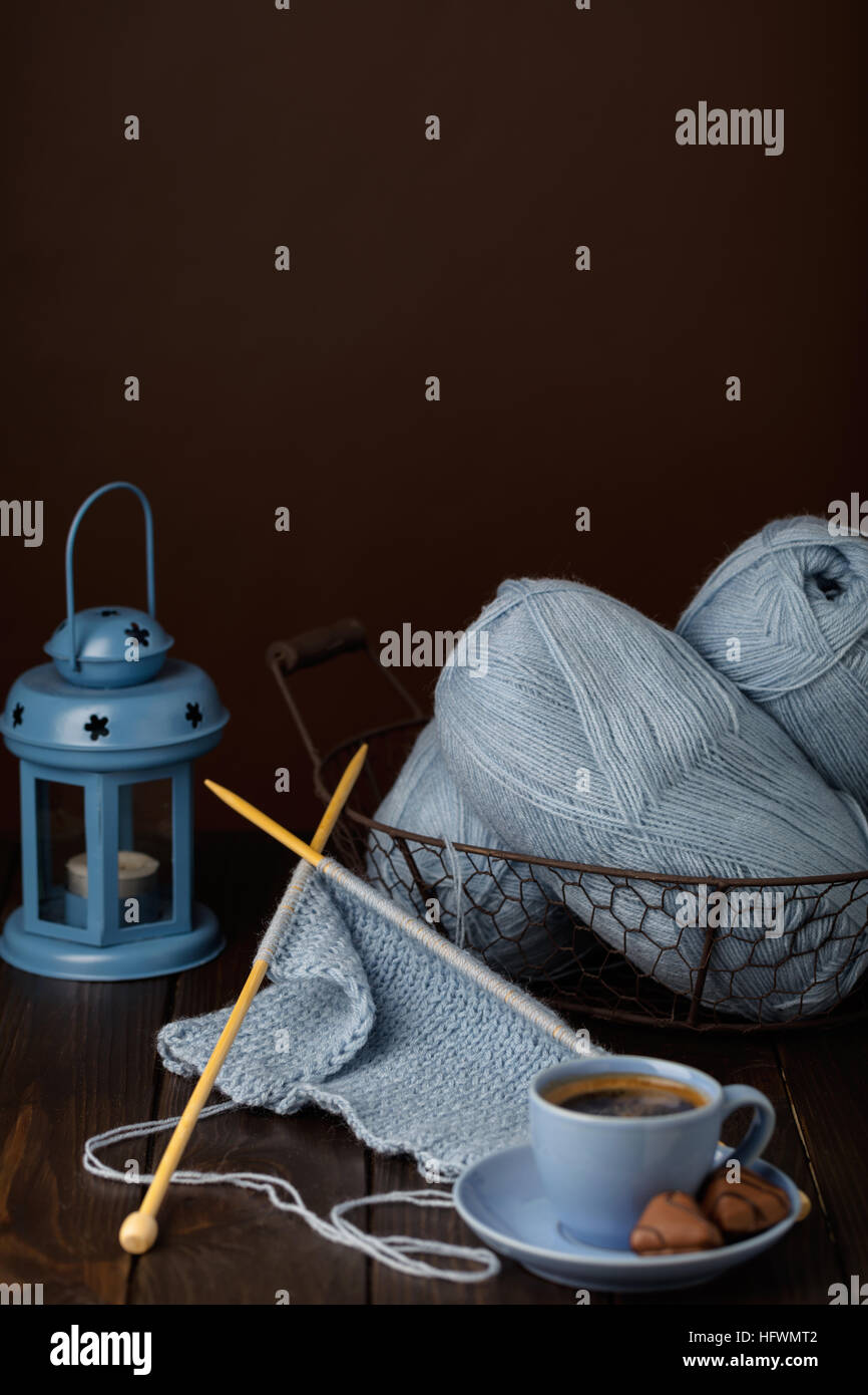 Knitting from light blue yarn. Cup of coffee and chocolates. Stock Photo