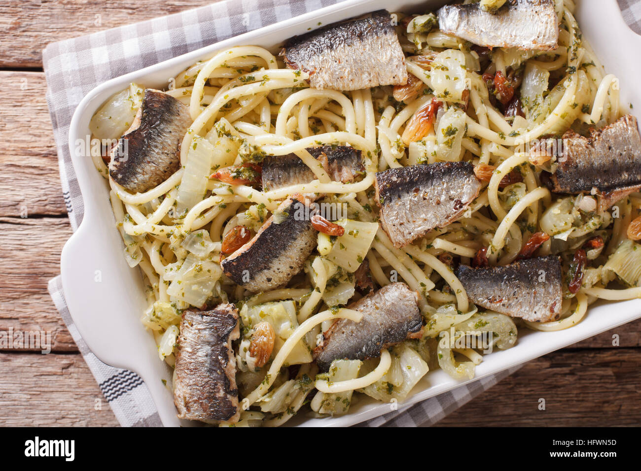 Italian pasta bucatini with sardines, fennel, raisins and pine nuts close up in baking dish. horizontal view from above Stock Photo