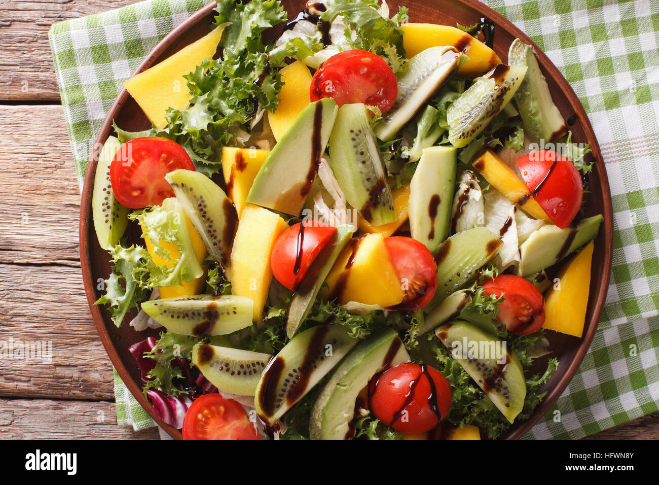 Fruit vegetable salad of mango, avocado, kiwi, tomato and lettuce on a plate close-up. Horizontal view from above Stock Photo