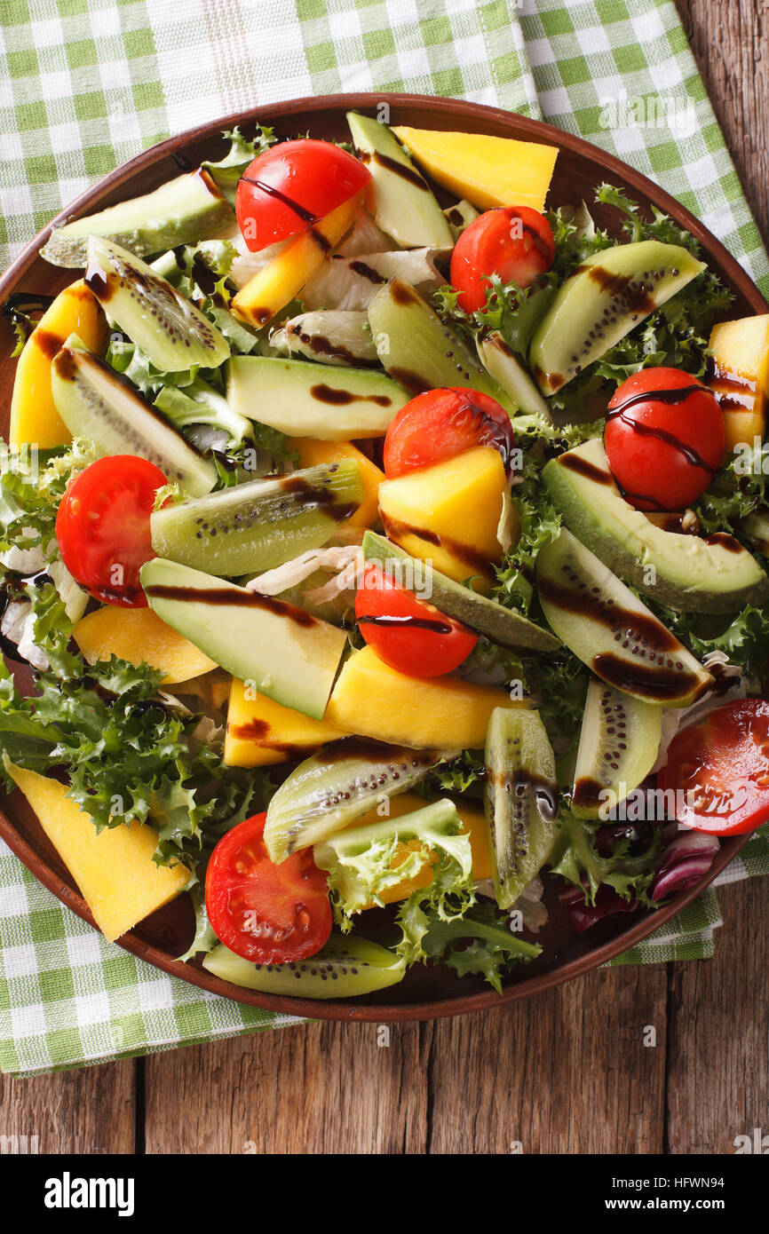 Fruit vegetable salad of mango, avocado, kiwi, tomato and lettuce on a plate close-up. vertical view from above Stock Photo