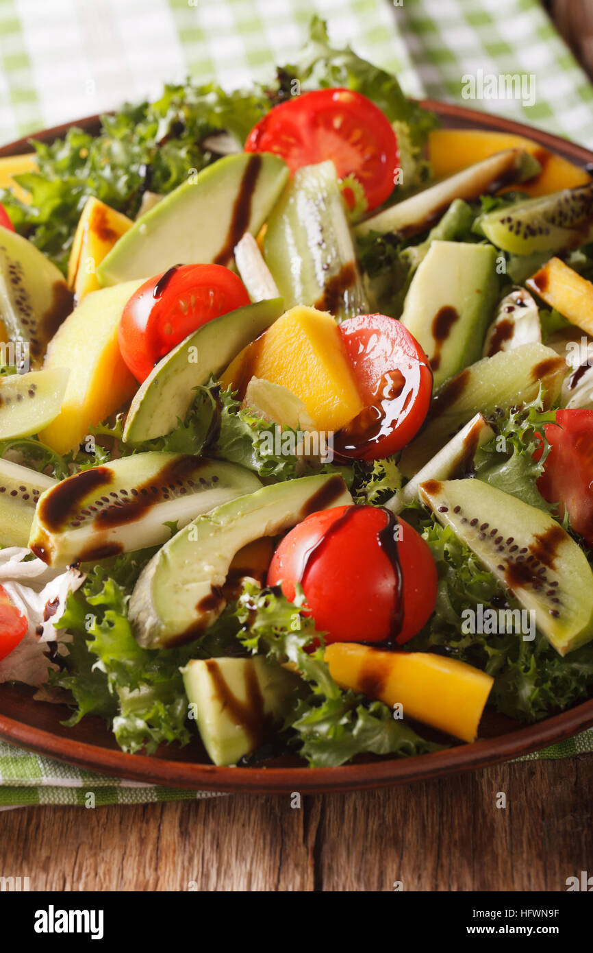 Fresh salad of mango, avocado, kiwi, tomato and lettuce on a plate close-up. vertical Stock Photo