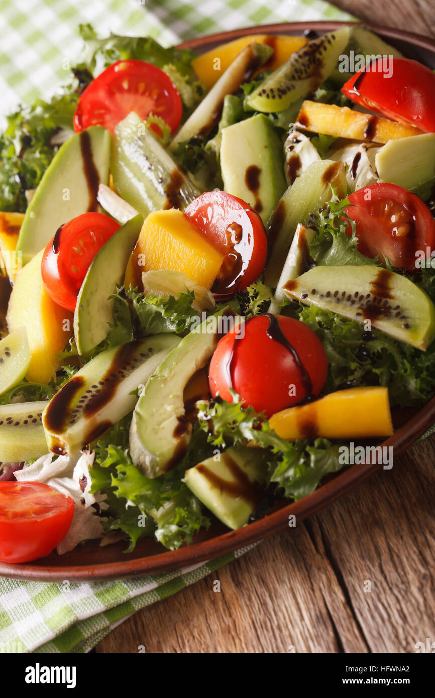Fruit vegetable salad of mango, avocado, kiwi, tomato and lettuce on a plate close-up. Vertical Stock Photo