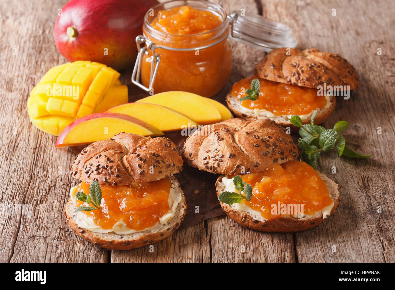 Buns with mango marmalade, butter and decorated with mint close up on