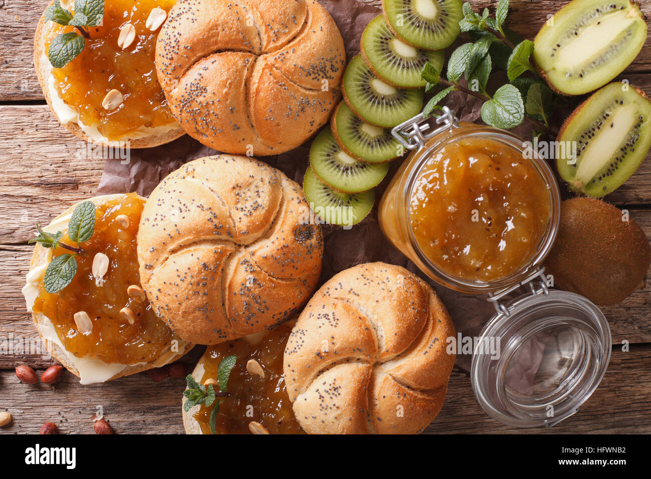 Delicious buns with butter, fruit jam kiwi, mint and peanuts closeup
