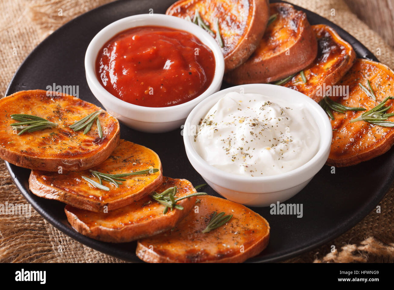 Grilled sweet potatoes with sour cream and ketchup closeup on a plate