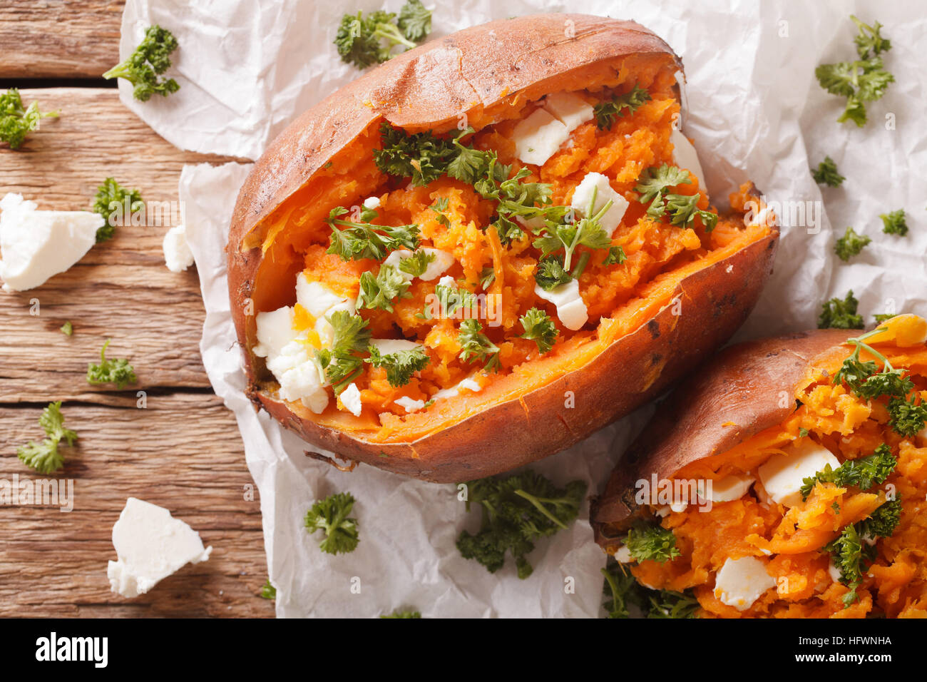 healthy food: baked sweet potato stuffed with feta cheese and parsley close-up on the table. horizontal view from above Stock Photo
