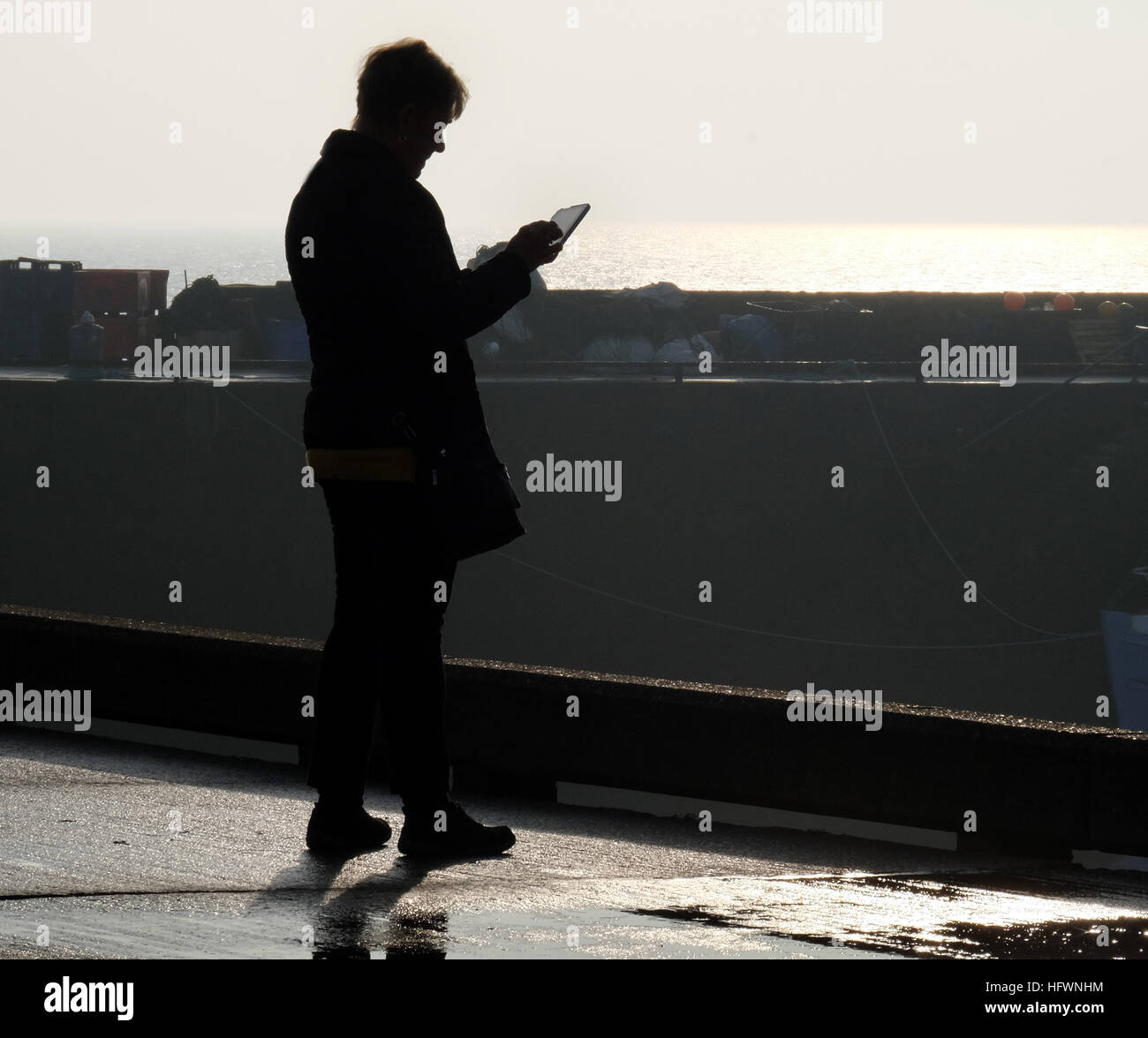 Woman taking pictures with tablet computer on harbor wall. Stock Photo