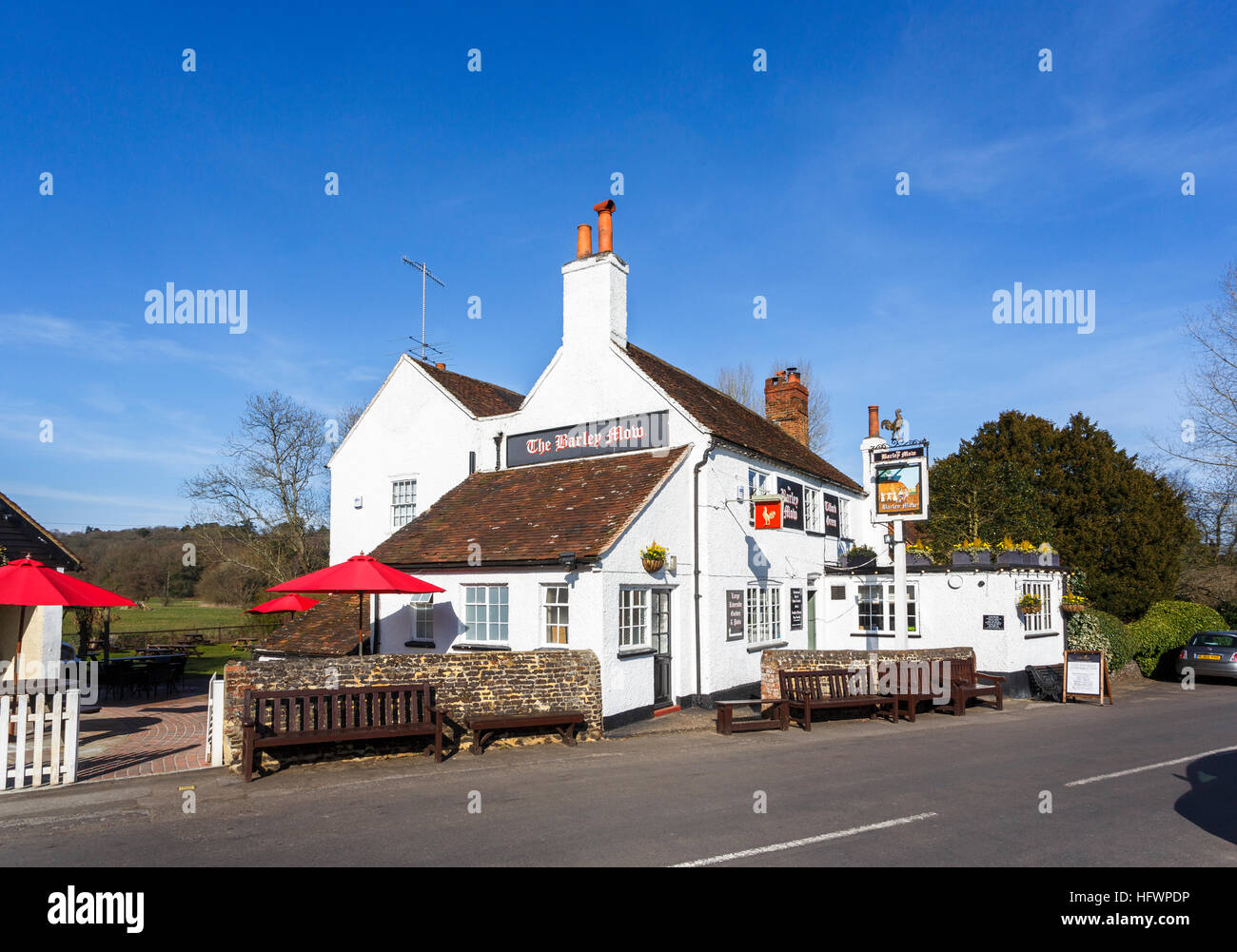 The Barley Mow, a traditional whitewashed country pub on Tilford Green in Tilford, a small village near Farnham, Surrey, UK, on a spring day with blue Stock Photo