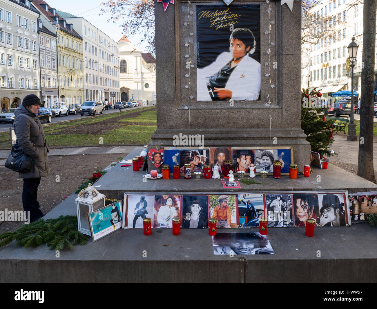 Munich, Germany - December 29, 2016: A woman is standing next to the so called 'Michael Jackson Memorial' at Munich's Promenadeplatz across the hotel 'Bayerischer Hof' and is looking at votive candles, pictures and memorabilia of the late pop star Michael Jackson. Since the death of the artist in 2009, the historic stone monument of Orlando di Lasso has been converted into a shrine and memorial by fans of the 'King of Pop' who used to occupy a suite at the nearby luxury hotel when staying in Munich. Stock Photo