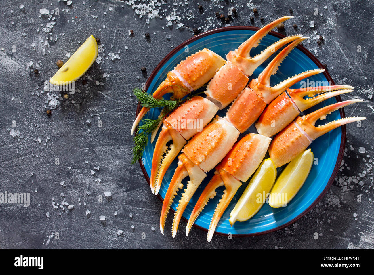 Cooked crab claws with lemon, sea salt and pepper on a concrete