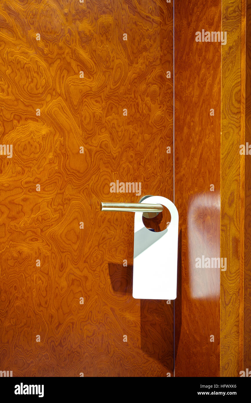 Hotel room closed door with white hanger, copy space for inscription like do not disturb or make up room. Stock Photo