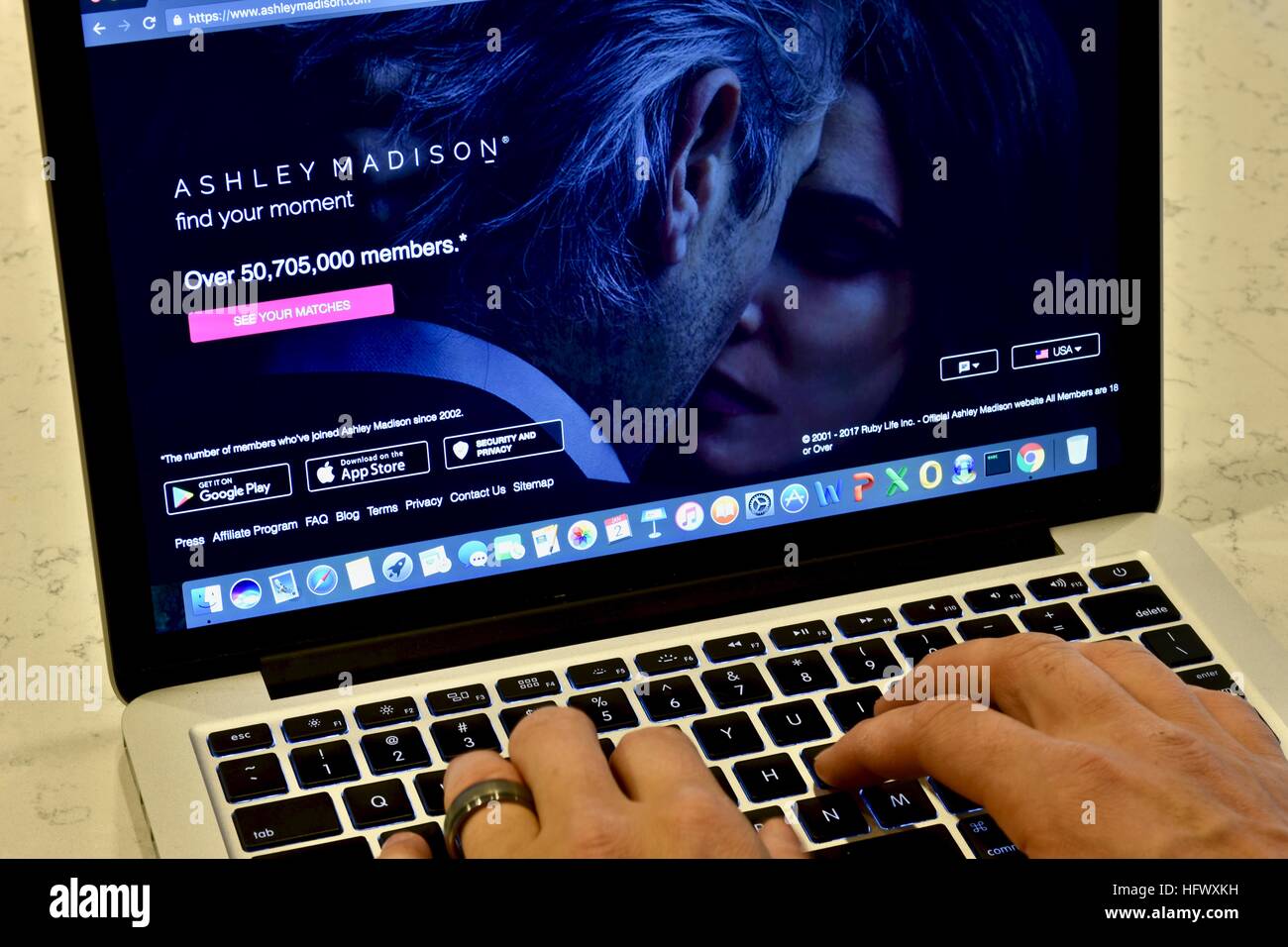 An Apple Macbook Pro displayed on a white marble surface with a married man viewing the Ashley Madison hookup website Stock Photo