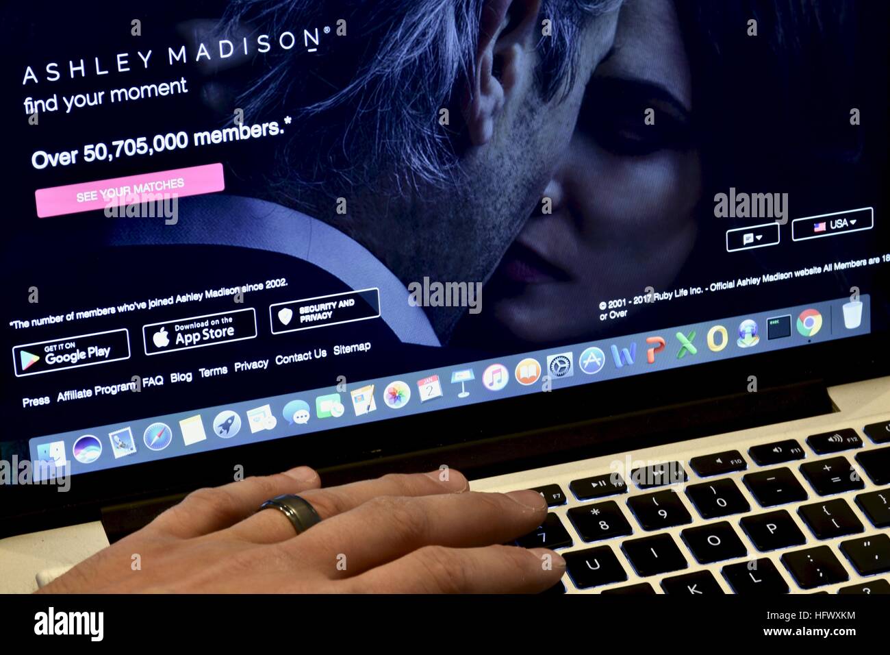 An Apple Macbook Pro displayed on a white marble surface with a married man viewing the Ashley Madison hookup website Stock Photo