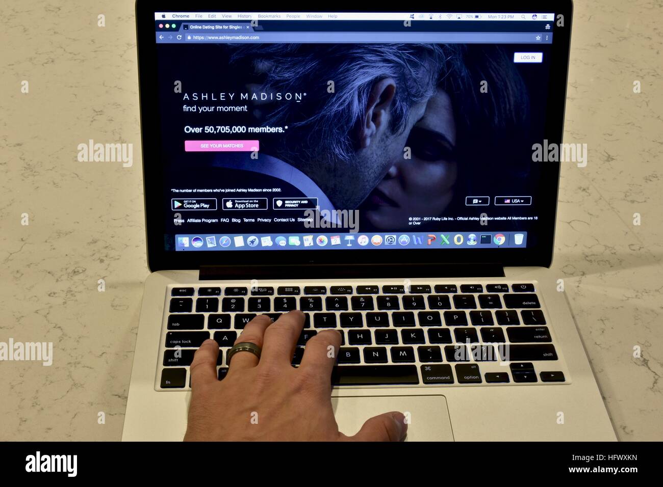 An Apple Macbook Pro displayed on a white marble surface with a married man viewing the Ashley Madison hookup website Stock Photo