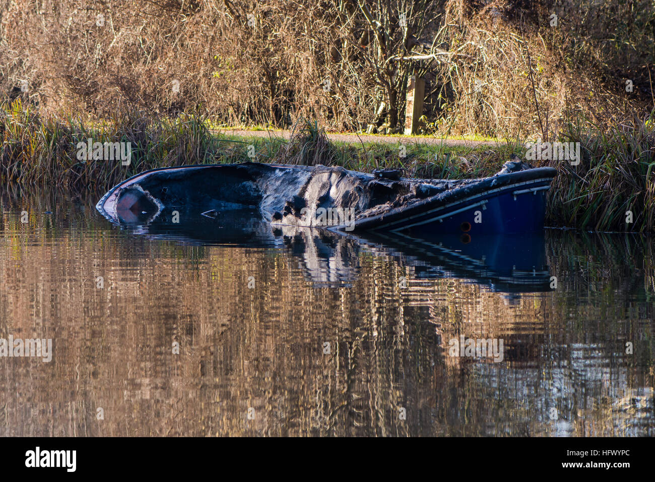 Partially submerged canal boat after fire. Damaged hull of narrow boat