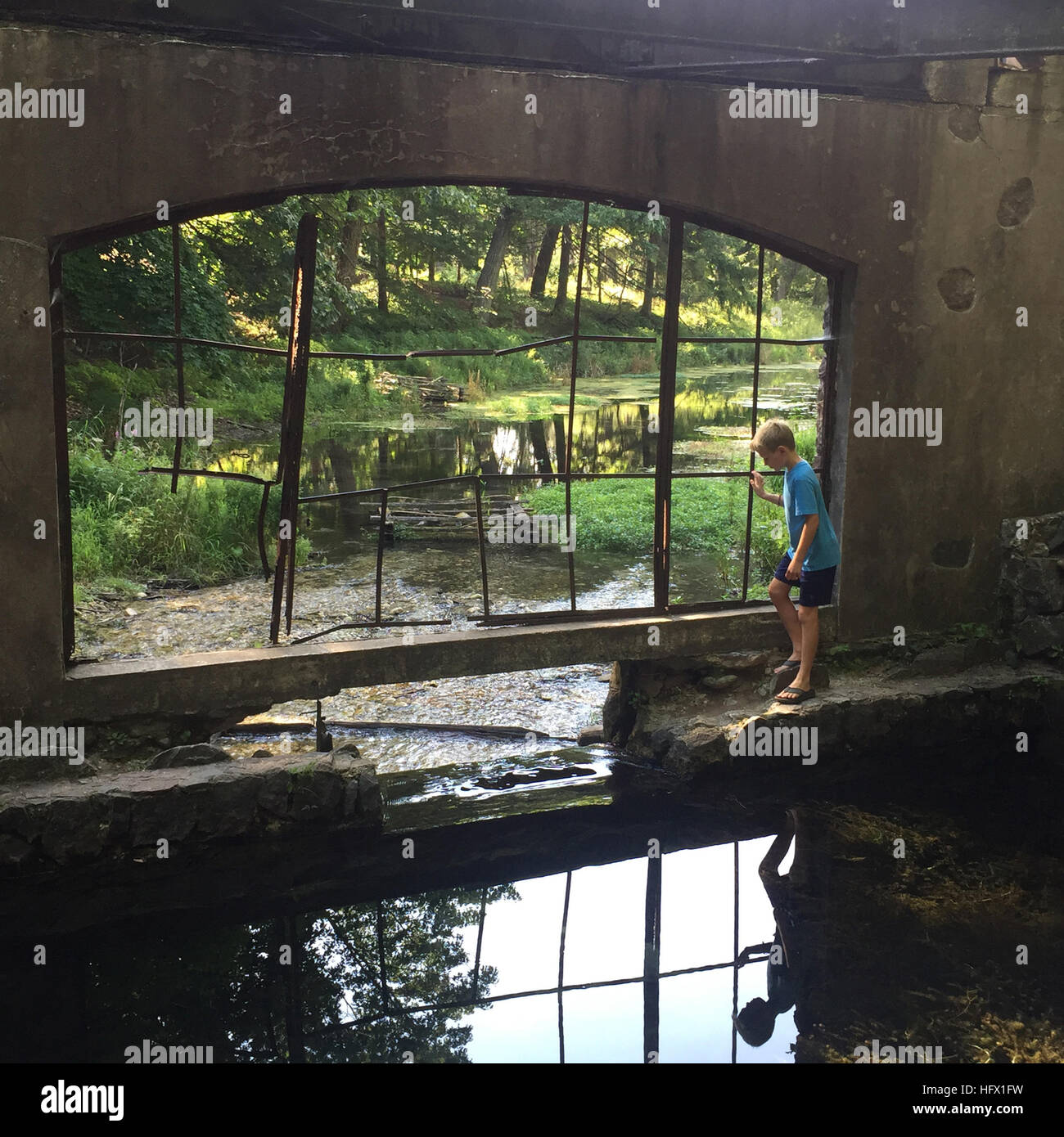 Nine-year-old Boy Exploring Stream under a Bridge, Paradise Springs, Wisconsin, USA. Stock Photo