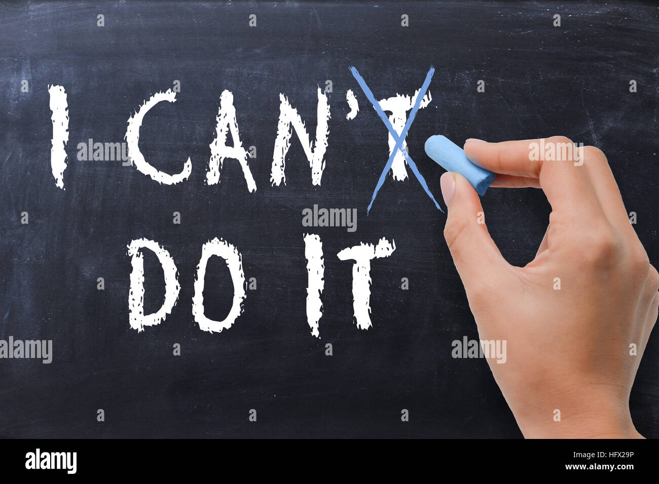 Motivational metaphor on blackboard with woman spelling the phrase “ I can do it” Stock Photo