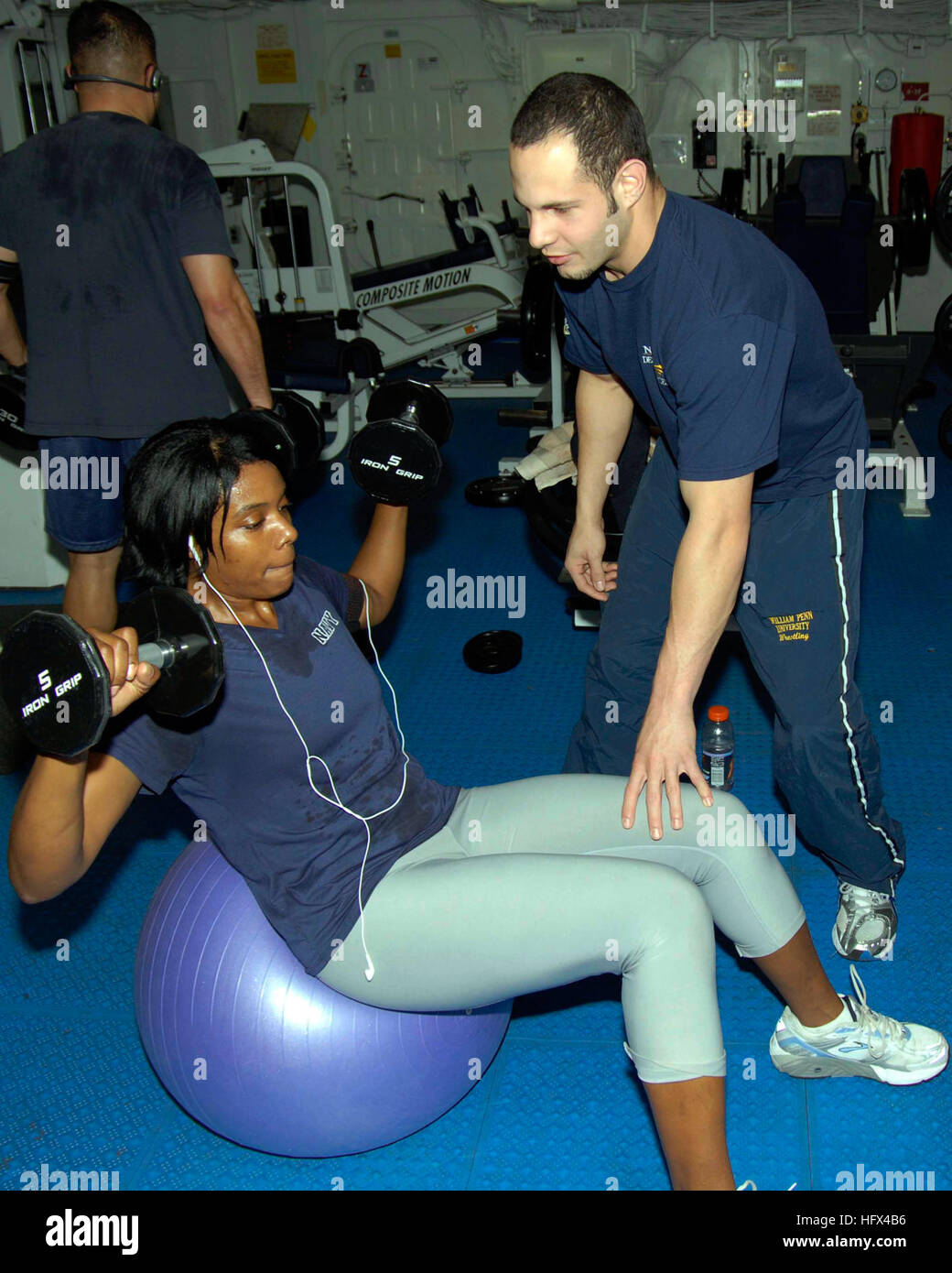 090115-N-9761H-009 PACIFIC OCEAN (Jan. 15, 2009) The ÒFit BossÓ from the amphibious assault ship USS Boxer (LHD 4) stabilizes a Sailor aboard Boxer as she performs weighted sit-ups on an exercise ball. Boxer is on a scheduled deployment in the western Pacific Ocean to provide global maritime security. (U.S. Navy photo by Mass Communication Specialist 2nd Class Jeff Hopkins/Released) Weighted sit-ups on an exercise ball Stock Photo