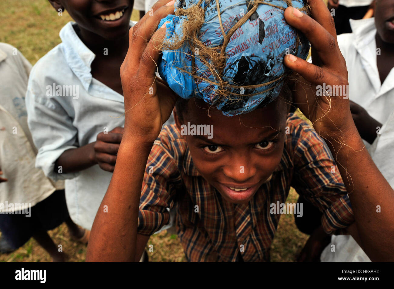 A boy holds a soccer ball made of plastic bags on his head before a