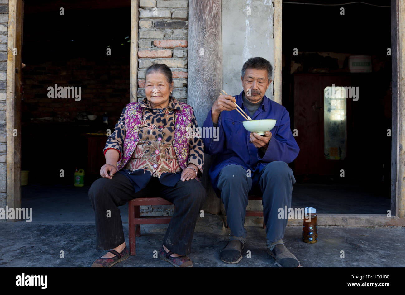 An old married couple sitting outside their farmhouse in a small peasant village in Gansu in China. Stock Photo