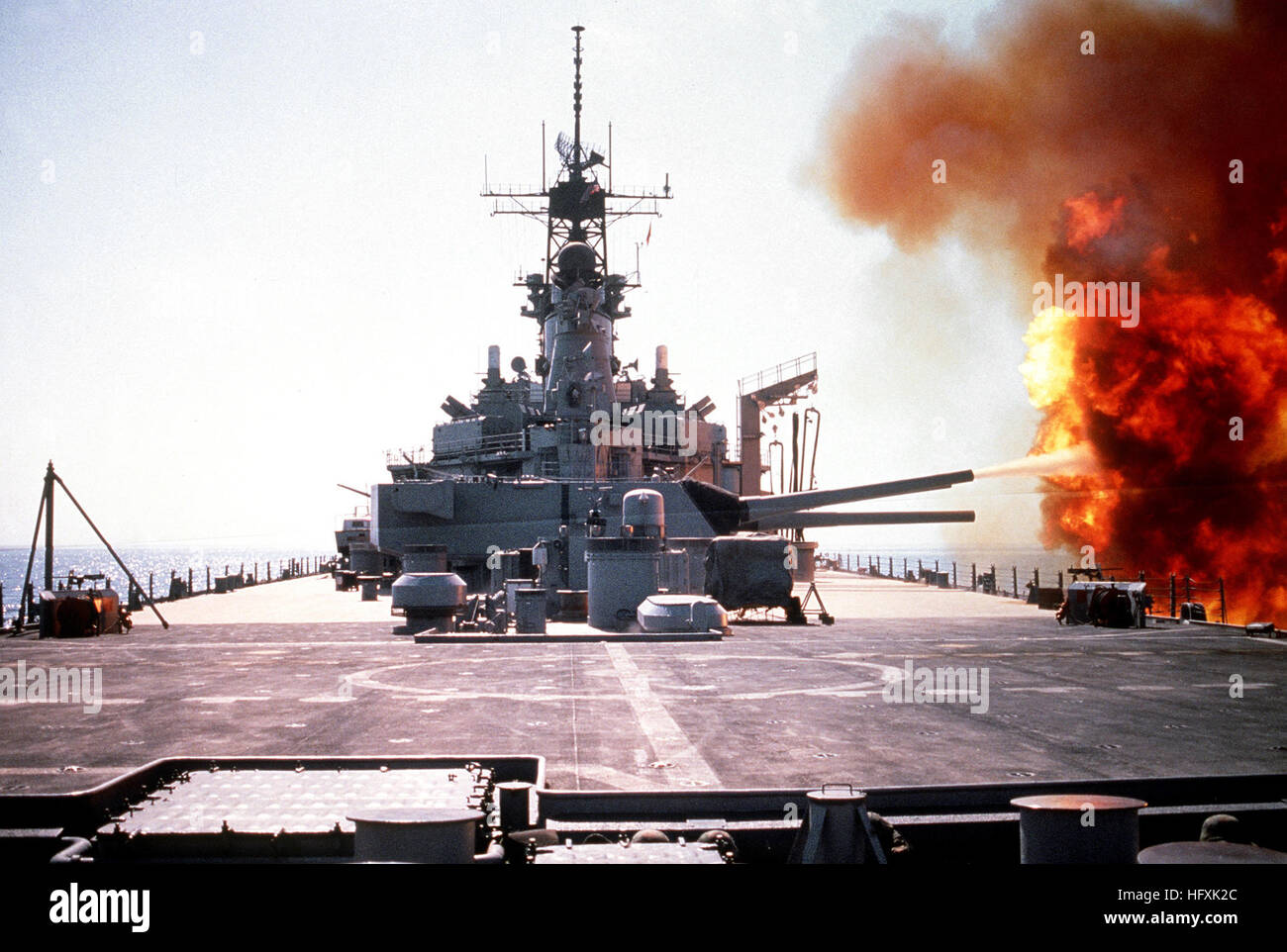 The battleship USS WISCONSIN (BB-64) fires a round from one of the Mark 7 16-inch/50-caliber guns in its No. 3 turret during Operation Desert Storm.  The ship's target is an Iraqi artillery battery in southern Kuwaiti. Wisconsin Shoots Stock Photo