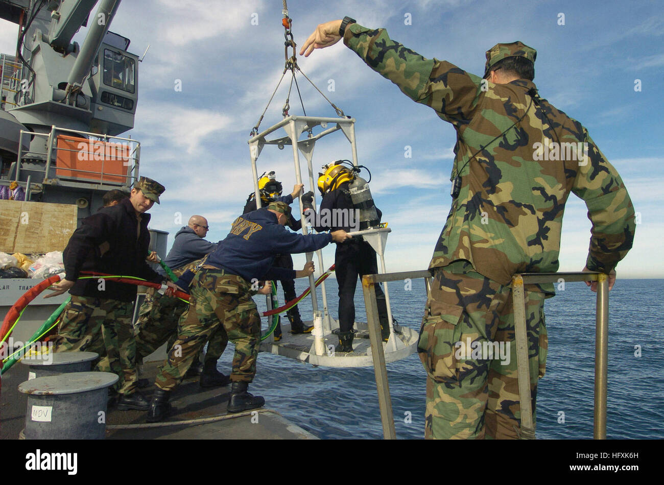 US Navy (USN) Chief Boatswain's Mate (BMC) Paul Adams (foreground) supervises as two Navy Divers are lowered into the waters of the Pacific Ocean. USN Divers from Southwest Regional Maintenance Center (SWRMC), Mobile Diving and Salvage Unit (MDSU) DET-1, and Explosive Ordinance Disposal (EOD) Unit 3, are conducting training onboard USN Military Sealift Command (MSC) Powhatan Class Fleet Ocean Tug, USNS NAVAJO (T-ATF 169) to allow a prescreening for those, such as Adams, pursuing Master Diver Qualifications. USNS Navajo (T-ATF 169) diving training Stock Photo