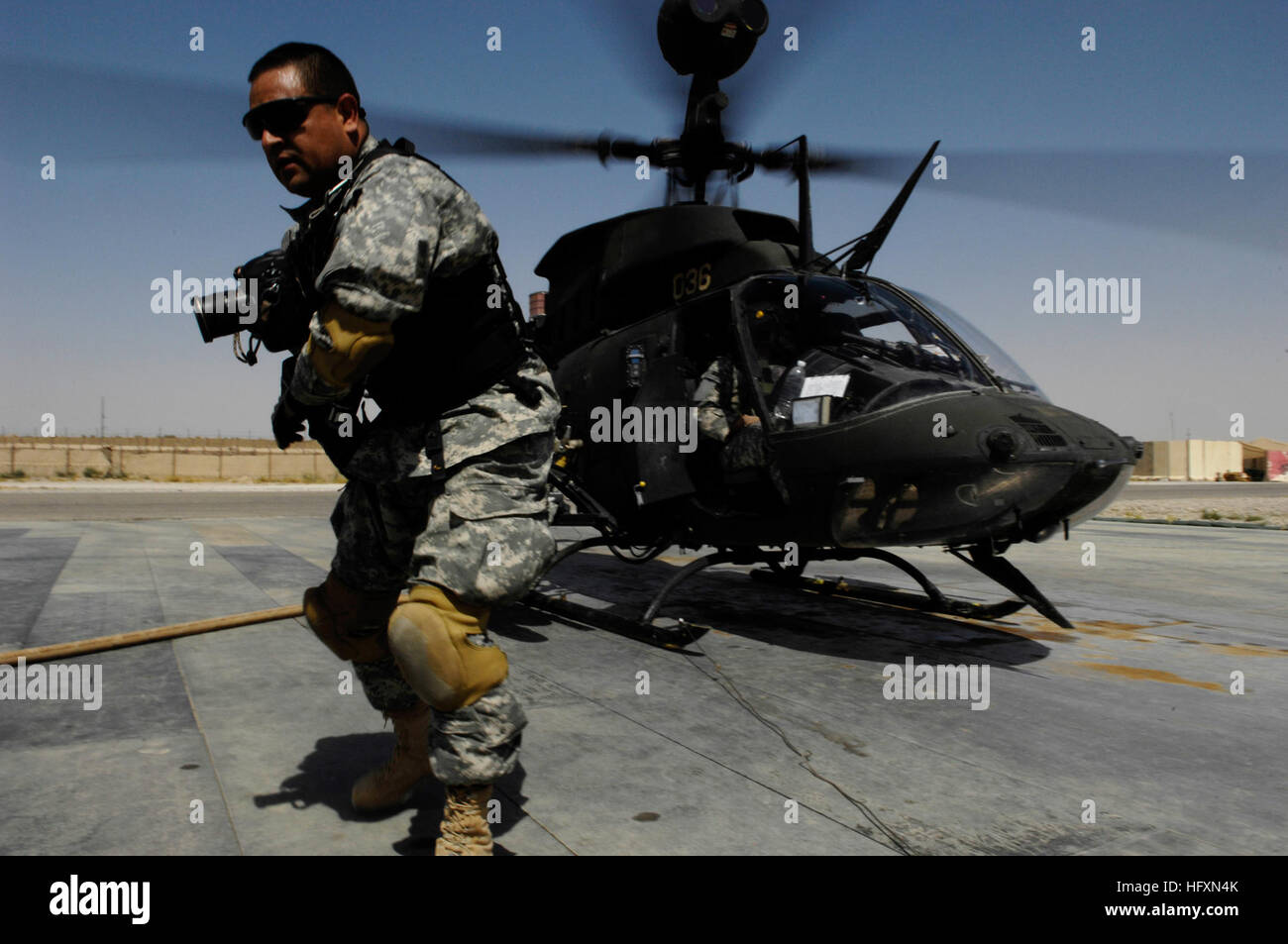 090717-F-7478C-012 MOSUL, Iraq (July 17, 2009) Mass Communication Specialist 1st Class Carmichael Yepez, assigned to Multi-National Corps-Iraq, Joint Combat Camera, moves to clear the helicopter pad after capturing video and photo of a UH-58 Delta helicopter refueling and reloading munitions at Forward Operating Base Diamondback, near Mosul, Iraq.  (U.S. Air Force photo by Senior Airman Kamaile Chan/Released) US Navy 090717-F-7478C-012 Mass Communication Specialist 1st Class Carmichael Yepez, assigned to Multi-National Corps-Iraq, Joint Combat Camera, moves to clear the helicopter pad after ca Stock Photo