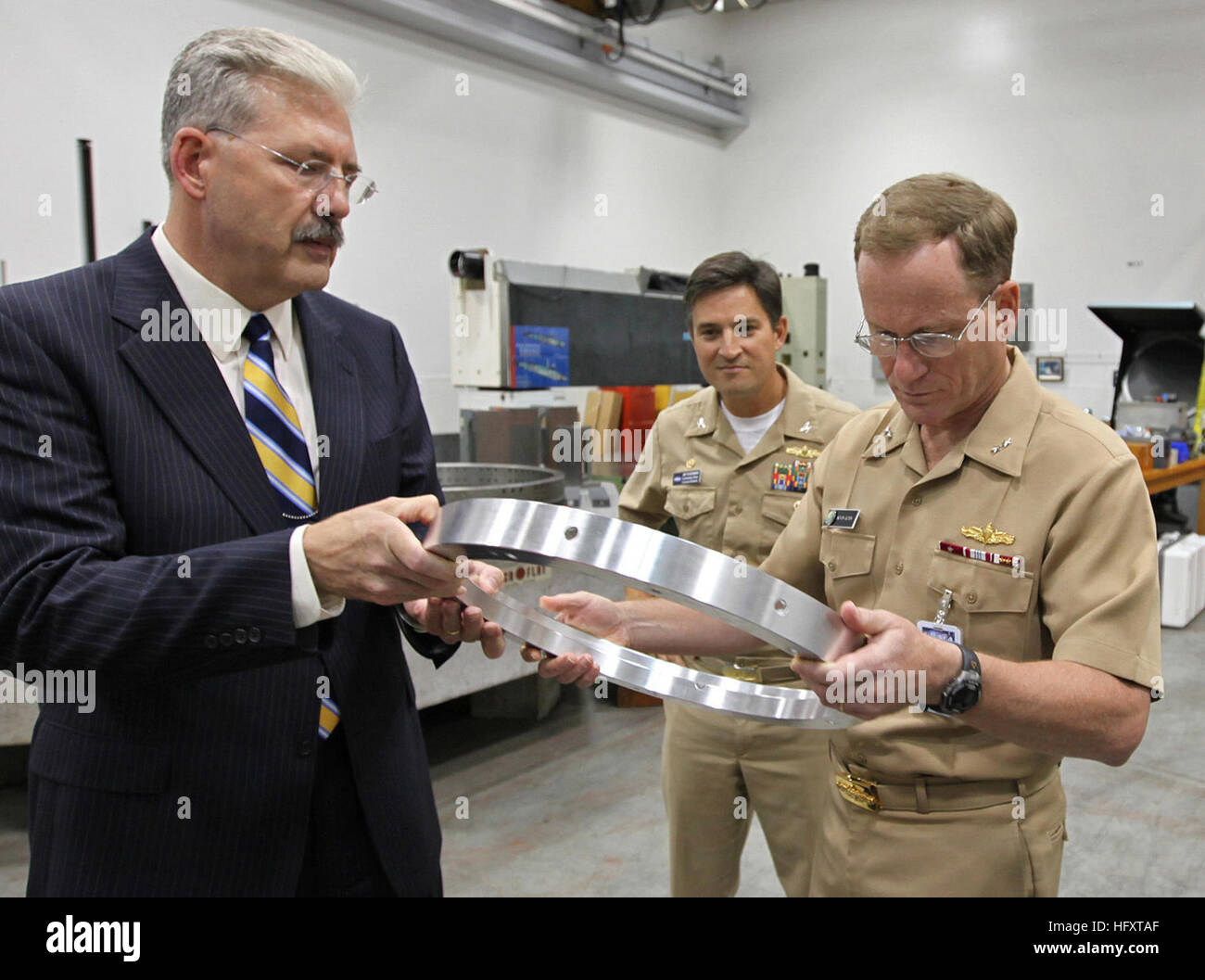 090929-N-8863V-015 NORCO, Calif. (Sept 29, 2009) Dr. William Luebke, technical director of Naval Surface Warfare Center, Corona, left, shows a prototype interface gage to Rear Adm. Kevin Quinn, commander, Naval Surface Force Atlantic, as Capt. Jay Kadowaki, commanding officer of Naval Surface Warfare Center Corona, looks on during a tour of the Measurement Science & Technology Laboratory at Naval Surface Warfare Center Corona. Quinn visited Naval Surface Warfare Center to gain a greater understanding of its capabilities to leverage talents and improve surface force readiness. (U.S. Navy Photo  Stock Photo