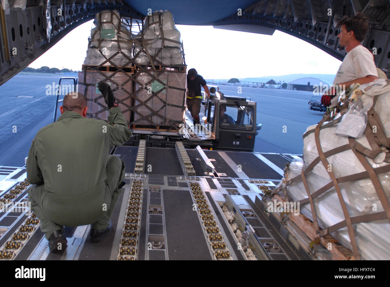 090930-F-9708M-072 HICKAM AIR FORCE BASE, Hawaii (Sept. 30, 2009) Tech. Sgt. Kimo McKee, assigned to the Hawaii Air National Guard, directs the loading of humanitarian supplies from the Federal Emergency Management Agency into a C-17 Globemaster III cargo aircraft. The supplies are for delivery to American Samoa to assist in relief efforts after a tsunami struck the island. The tsunami was triggered by an undersea earthquake Sept. 29.  (U.S. Air Force photo by Staff Sgt. Mike Meares/Released) US Navy 090930-F-9708M-072 Tech. Sgt. Kimo McKee, assigned to the Hawaii Air National Guard, directs t Stock Photo