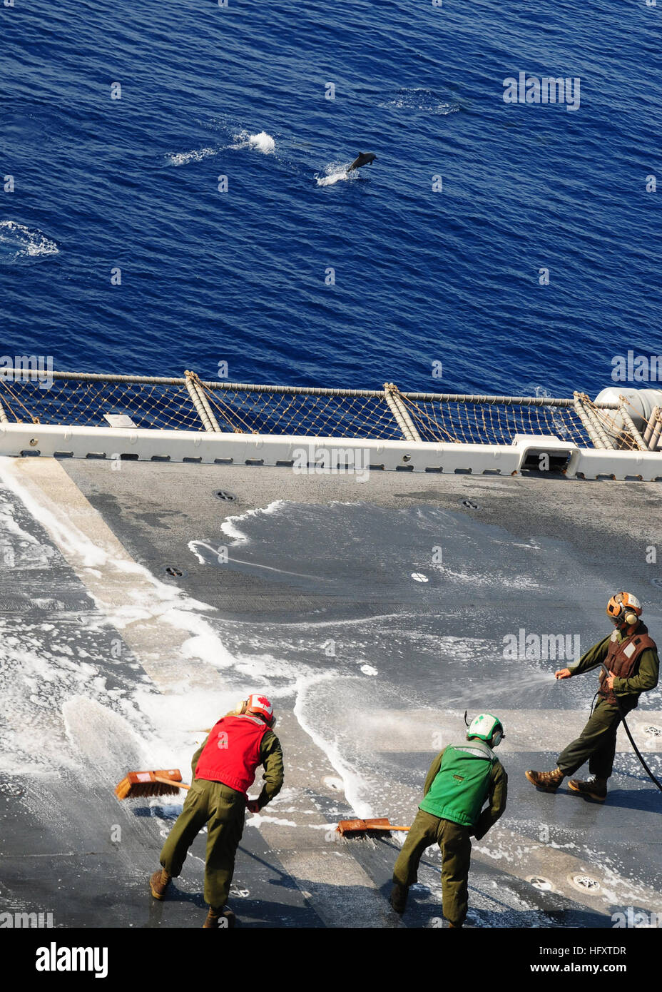 091002-N-3165S-231 U.S. 5TH FLEET AREA OF RESPONSIBILITY (Oct. 2, 2009) Marines from Marine Medium Tiltrotor Squadron (VMM) 263 (Reinforced), 22nd Marine Expeditionary Unit (22nd MEU), scrub the flight deck of the multi-purpose amphibious assault ship USS Bataan (LHD 5) while dolphins swim nearby. The Bataan Amphibious Ready Group is conducting maritime security operations in the U.S. 5th Fleet area of responsibility. (U.S. Navy photo by Mass Communication Specialist 3rd Class Ryan Steinhour/Released) US Navy 091002-N-3165S-231 Marines from Marine Medium Tiltrotor Squadron (VMM) 263 (Reinforce Stock Photo