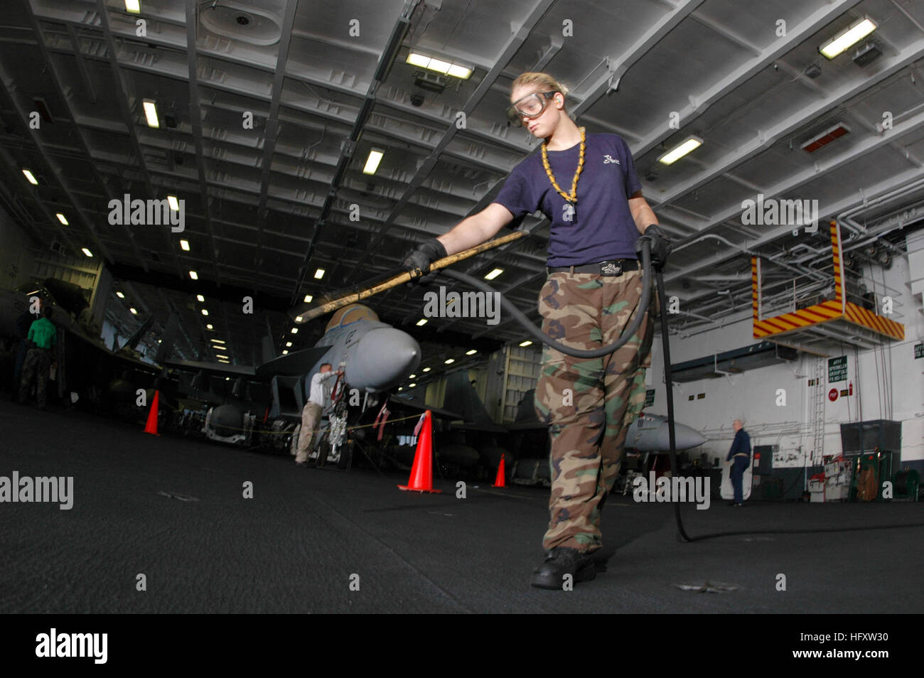 091014-N-2688M-009 INDIAN OCEAN (Oct. 14, 2009) Aviation Boatswain’s Mate (Handling) Airman Sarah Steinert uses a low-powered air blow-down hose to clear foreign objects and dirt off the deck of the hangar bay aboard the aircraft carrier USS Nimitz (CVN 68).  The Nimitz Carrier Strike Group is on a routine deployment to the U.S. 5th Fleet area of responsibility.  (U.S. Navy photo by Mass Communication Specialist 2nd Class Joseph H. Moon/Released) US Navy 091014-N-2688M-009 Aviation Boatswain's Mate (Handling) Airman Sarah Steinert uses a low-powered air blow-down hose Stock Photo