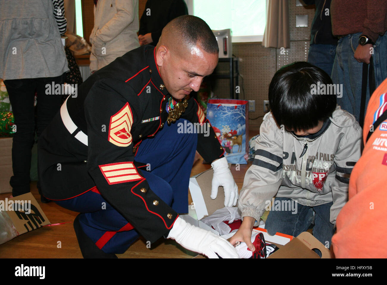 091205-N-1232V-058 YOKOSUKA, Japan (Dec. 5, 2009) Gunnery Sgt. Javier Andino, vice president of the Yokosuka Semper Fi Society and an employee of the Fleet and Industrial Supply Center Yokosuka, helps a resident of the St. Joseph Children’s Home in Tokyo unwrap his new shoes. Volunteers from the Yokosuka Base community collected donations of new clothes and brought them to the children. Andino also delivered toys donated through the Yokosuka Toys for Tots program. (U.S. Navy photo by Blake Vives/Released) US Navy 091205-N-1232V-058 Gunnery Sgt. Javier Andino helps a resident of the St. Joseph  Stock Photo