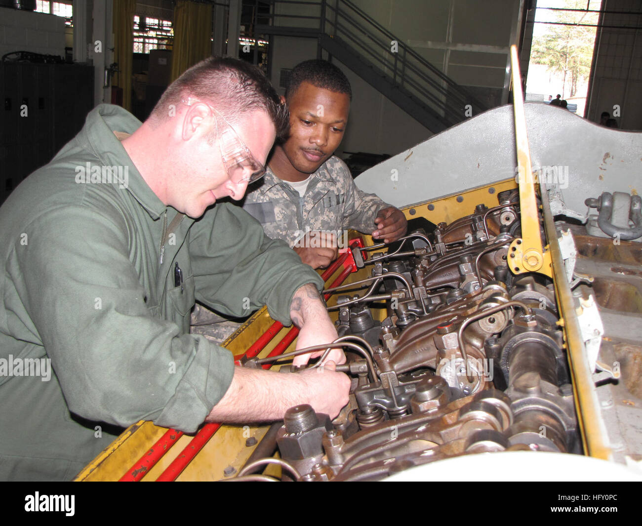 100125-N-0563C-004 FORT BELVOIR, Va. (Jan. 25, 2010) Construction Mechanic  1st Class Jason Duncan, left, adjusts the fuel rack on a diesel engine  trainer as Army Sgt. Hairston observes at the mechanical specialty