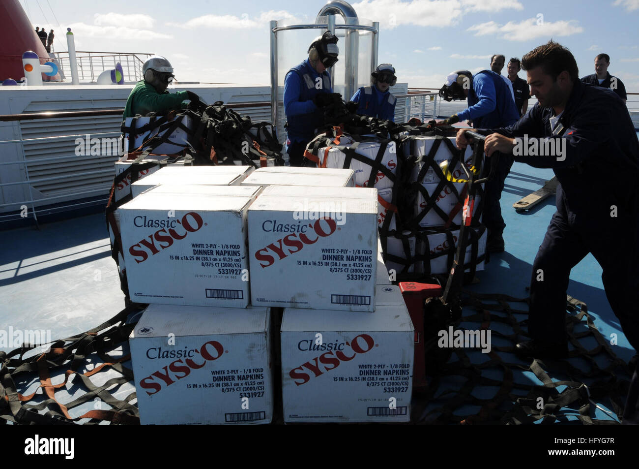 Sailors assigned to the aircraft carrier USS Ronald Reagan (CVN 76) and crew members of Carnival cruise ship C/V Splendor unload pallets of food on the weather-deck of the cruise ship during an emergency vertical replenishment. Ronald Reagan was diverted from its current training maneuvers at the direction of Commander U.S. Third Fleet, and at the request of the U.S. Coast Guard, to a position south near the Carnival cruise ship C/V Splendor to facilitate the delivery of 4,500 pounds of supplies to the cruise ship. Early Monday, CV Splendor reported it was dead in the water 150 nautical miles  Stock Photo