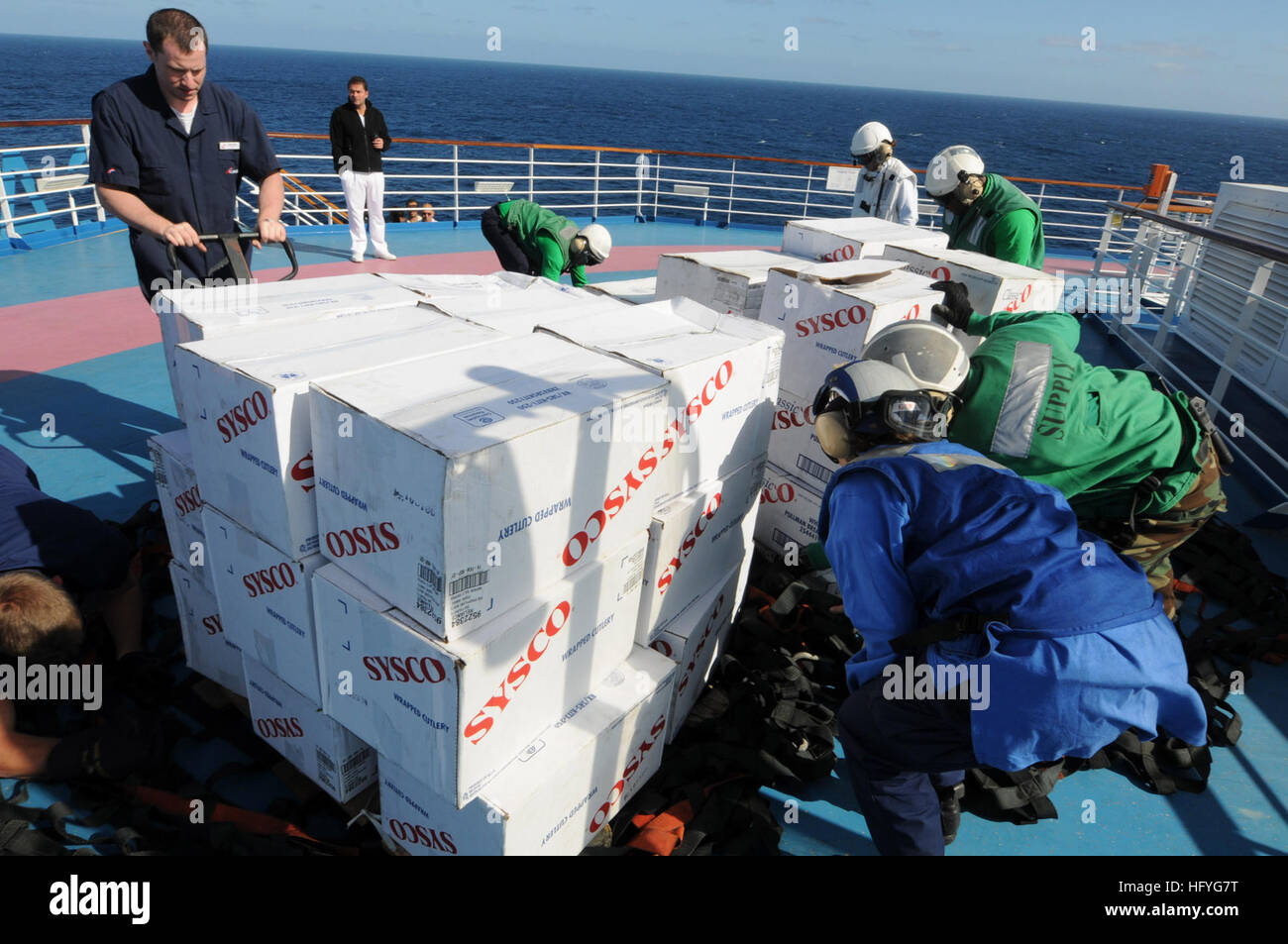Sailors assigned to the aircraft carrier USS Ronald Reagan (CVN 76) and crew members of Carnival cruise ship C/V Splendor unload pallets of food on the weather-deck of the cruise ship during an emergency vertical replenishment. Ronald Reagan was diverted from its current training maneuvers at the direction of Commander U.S. Third Fleet, and at the request of the U.S. Coast Guard, to a position south near the Carnival cruise ship C/V Splendor to facilitate the delivery of 4,500 pounds of supplies to the cruise ship. Early Monday, CV Splendor reported it was dead in the water 150 nautical miles  Stock Photo